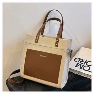 Detail view of large canvas tote bag with brown leather pocket and MYCARE lettering