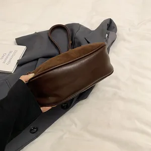 Détail du patchwork en daim marron et cuir lisse sur un sac à bandoulière en croissant