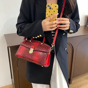 Detail der roten Handtasche mit Schlangenmuster und goldenem Drehverschluss am Model