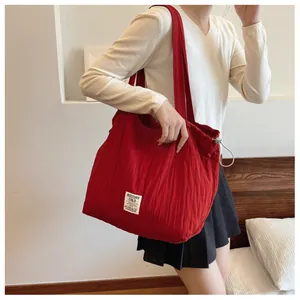 Close-up of a red drawstring nylon shoulder bag featuring a white logo patch detail