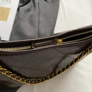 Detail of quilted leather handbag with gold metal zipper and chain strap detail