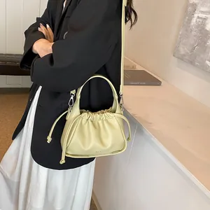 Detail view of cream puff crossbody bag with drawstring closure and soft pleated texture