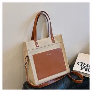 Detail of canvas tote bag with brown leather pocket and adjustable shoulder strap