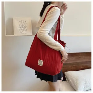 Close-up of red striped quilted nylon tote bag with drawstring and white brand label