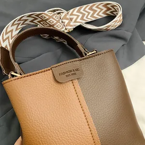 Detailed close-up of the contrast stitching and pebbled leather texture on the bucket bag