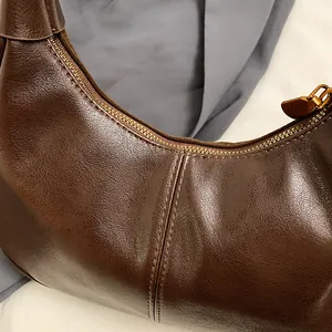 Détail du sac hobo en cuir marron foncé avec fermeture éclair en métal et double couture