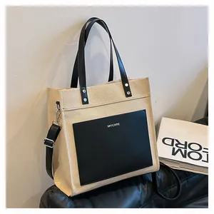 Detail of canvas tote bag featuring leather pocket and MYCARE logo on a sofa