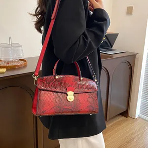 Detail der roten Schlangenmuster-Handtasche mit goldener Metallschnalle und Trageriemen