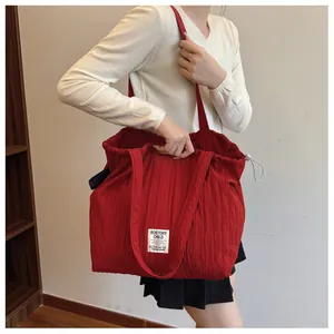 Close-up of red pleated nylon tote bag featuring drawstring closure and brand woven label
