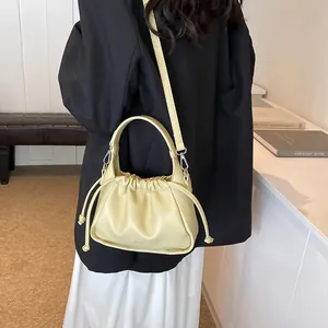 Detail view of cream drawstring cloud bag featuring soft pleated leather and slim crossbody strap