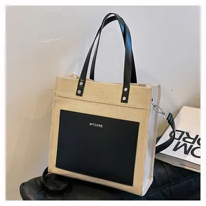 Detail showing high-quality canvas texture and premium black leather stitching on tote bag