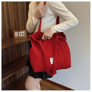Close-up of red pleated nylon tote bag with drawstring detail and white logo label