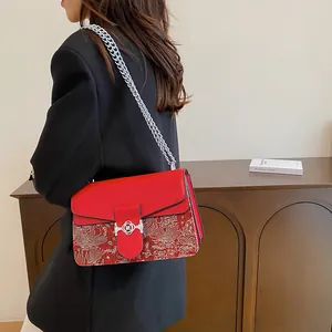Detailed silver floral embroidery and round metal clasp on red leather crossbody bag