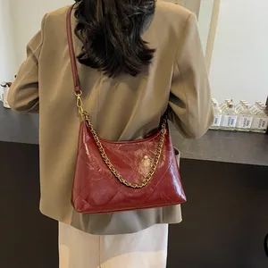 Close-up of wine red quilted shoulder bag with gold chain and crossbody strap details