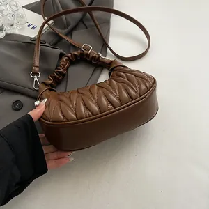 Close-up of brown pleated cloud bag with matelassé texture and thin shoulder strap
