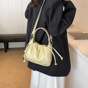 Detail of light yellow pleated cloud bag with adjustable strap and silver metal hooks