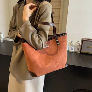 Detail of large brown suede tote bag with leather straps on model in stylish interior