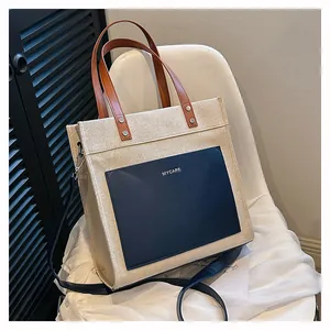 Close-up of contrast canvas tote bag featuring navy front pocket with MYCARE logo text