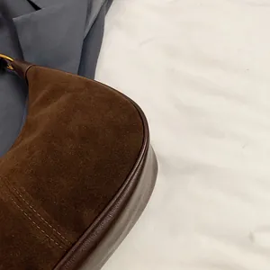 Détail du sac à main en daim marron foncé montrant les coutures et la texture