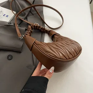 Close-up of deep brown pleated crescent bag with quilted texture and soft PU leather