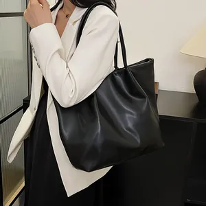 Minimalist large black PU leather tote bag shown on model with white blazer