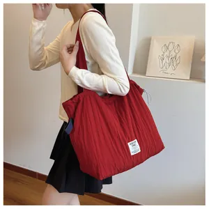 Detail shot of the vertical pleated texture and logo on this red nylon tote shoulder bag