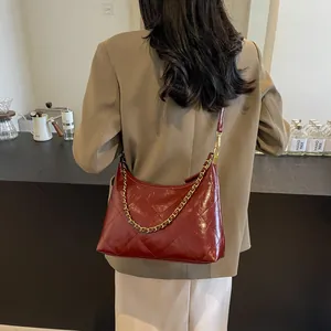 Close-up of red quilted leather shoulder bag with gold chain strap on a model