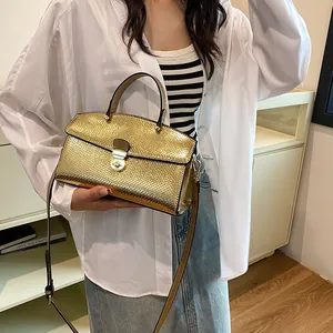 Detail der goldenen Handtasche mit Schlangenmuster, Metallschnalle und Griff, von Model gehalten