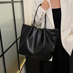 Close-up of minimalist black PU leather tote bag with soft pleated design and slim handles