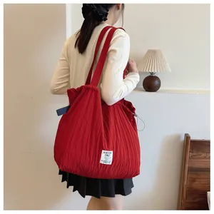 Detail of red pleated nylon tote bag featuring drawstring closure and brand label