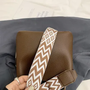 Detail of vintage brown bucket bag with lychee texture and geometric fabric strap