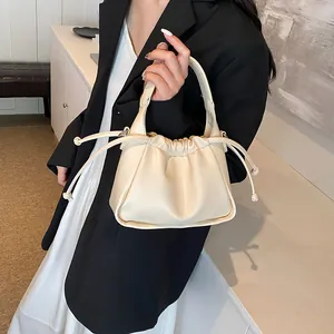 Detailed shot of cream ruched leather handbag with drawstring closure and fine text engraving