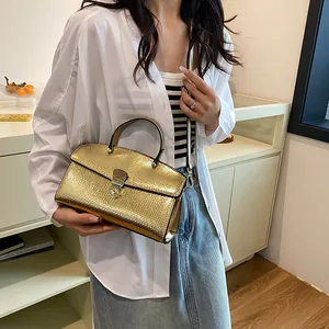 Detail der goldmetallischen Handtasche mit Schlangenprägung und edlem Drehverschluss
