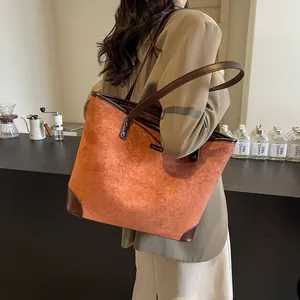 Close-up of brown suede tote bag with leather trim in a modern cafe setting
