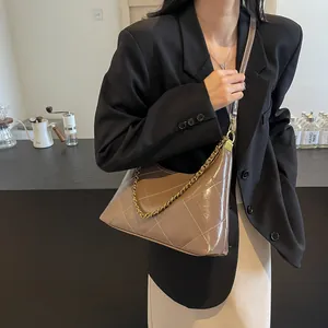 Close-up of brown quilted hobo bag with gold chain strap on model's shoulder
