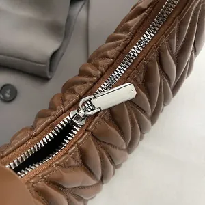 Detail of silver metal zipper and chevron quilted leather on brown vintage dumpling bag