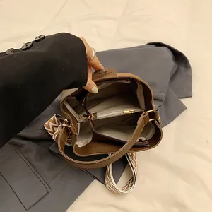 Interior detail of brown bucket bag showing triple compartments and striped strap