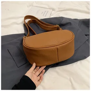 Détail de la texture grain litchi et boucle en métal doré sur le sac à bandoulière brun