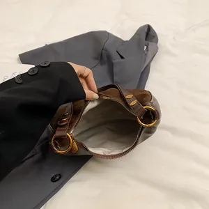 Détail d'un sac à main en cuir marron montrant l'intérieur spacieux en tissu gris et le zip