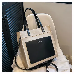 Close-up of beige canvas tote bag with black leather pocket and MYCARE logo detail