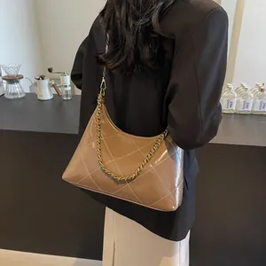 Detail of brown quilted leather bag with gold chain strap on a model shoulder
