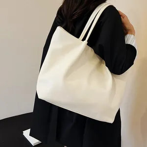 Detail view of large white faux leather tote bag showing soft texture and slim shoulder straps