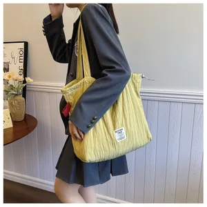 Detail of yellow quilted tote bag featuring textured fabric and brand label on shoulder strap