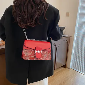 Detailed close-up of retro red patchwork bag with embroidery and silver chain strap