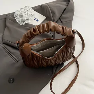 Detail of dark brown pleated handbag showing zipper pocket and soft leather texture