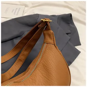 Détail du sac lune marron caramel avec texture de cuir grainé et fermeture éclair dorée
