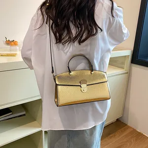 Detail der metallisch goldenen Handtasche mit Schlangenprägung und elegantem Griff