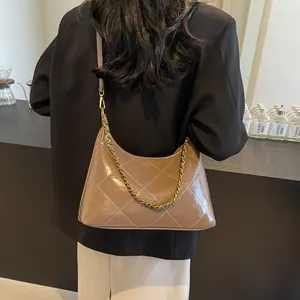 Detail of a brown quilted leather shoulder bag with gold chain and white contrast stitching