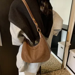 Détails d'un sac hobo en daim marron foncé avec bandoulière à boucle dorée ajustable