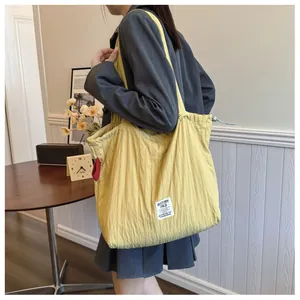 Macro detail of yellow nylon tote bag featuring a drawstring closure and brand label